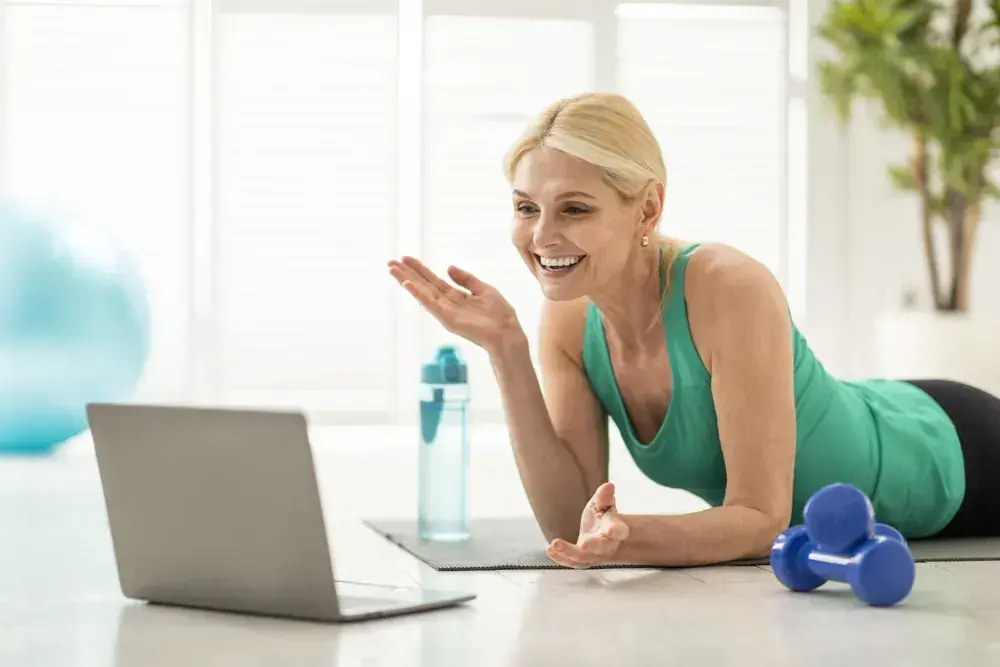 Mujer siguiendo una clase de entrenamiento online desde casa